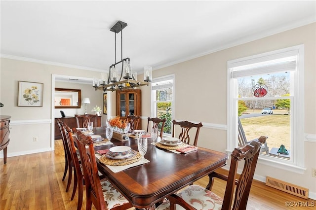 dining space featuring crown molding, visible vents, an inviting chandelier, light wood-style floors, and baseboards