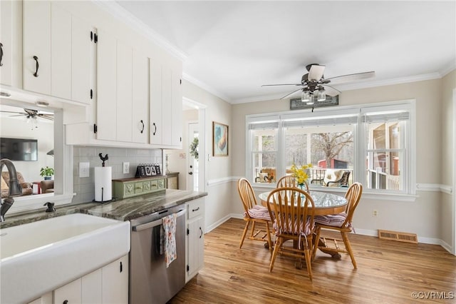 kitchen with light wood-style flooring, a sink, visible vents, decorative backsplash, and dishwasher