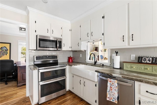 kitchen featuring white cabinets, ornamental molding, stainless steel appliances, and a sink