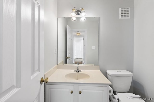 half bath with toilet, visible vents, and vanity