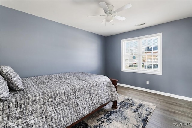 bedroom with ceiling fan, wood finished floors, visible vents, and baseboards