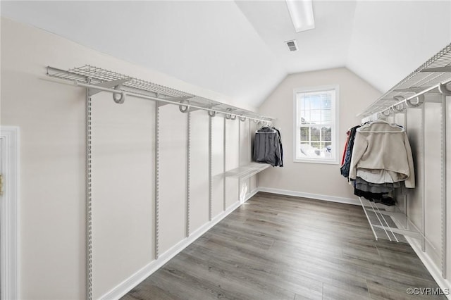 walk in closet with visible vents, vaulted ceiling, and wood finished floors