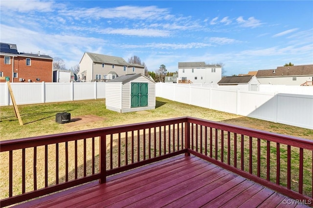 deck featuring a shed, a residential view, a fenced backyard, and an outbuilding