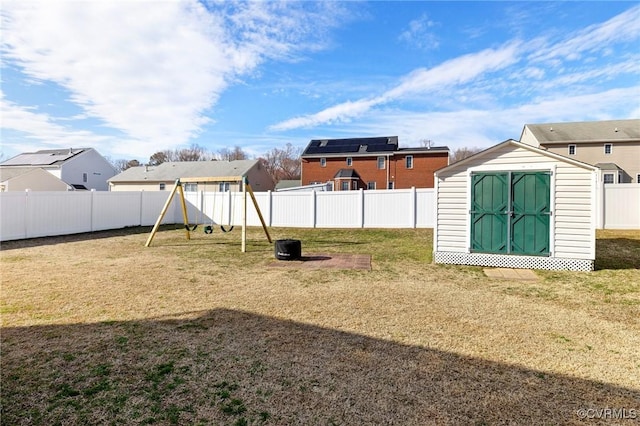 view of yard with a playground, a fenced backyard, a storage shed, an outdoor structure, and a residential view