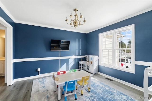 playroom with crown molding, visible vents, wood finished floors, a chandelier, and baseboards