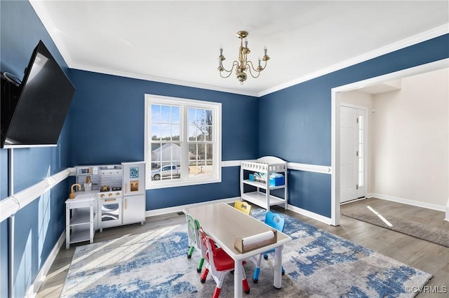 recreation room featuring crown molding, baseboards, wood finished floors, and an inviting chandelier