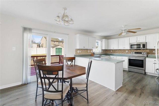 kitchen with appliances with stainless steel finishes, wood finished floors, white cabinets, and tasteful backsplash