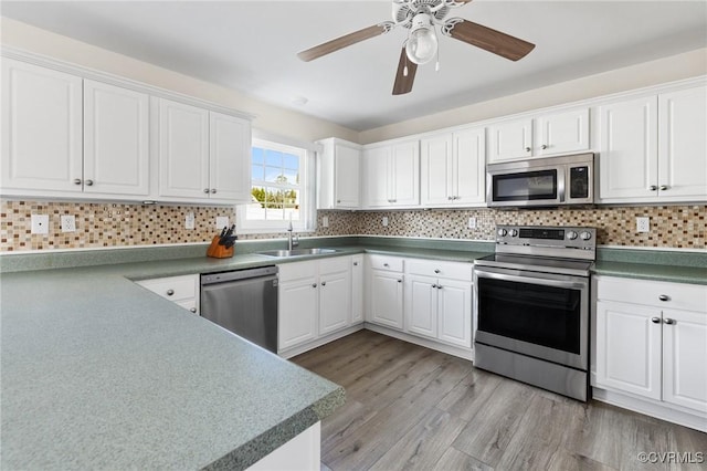 kitchen with stainless steel appliances, tasteful backsplash, a sink, and light wood-style flooring