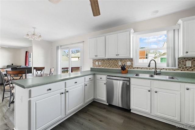 kitchen with plenty of natural light, dark wood finished floors, dishwasher, a peninsula, and a sink