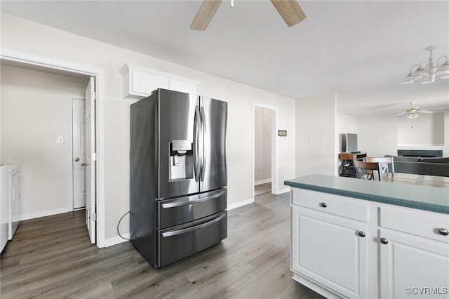 kitchen featuring a ceiling fan, white cabinets, wood finished floors, washer and dryer, and stainless steel fridge with ice dispenser