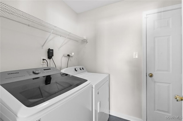 clothes washing area with washing machine and dryer, laundry area, and baseboards