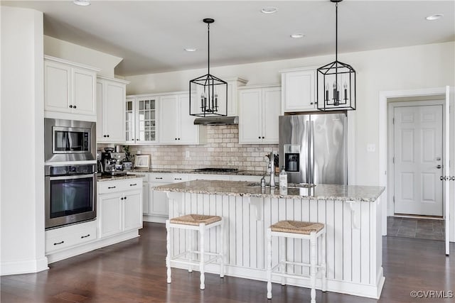 kitchen featuring tasteful backsplash, light stone counters, a kitchen island with sink, stainless steel appliances, and a sink