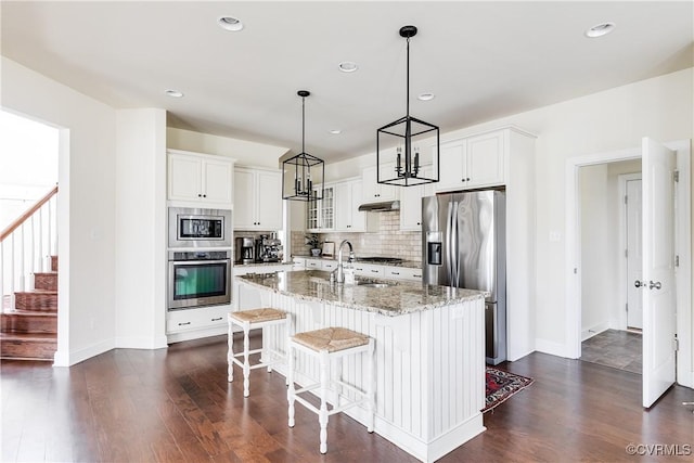 kitchen featuring stainless steel appliances, dark wood finished floors, a sink, and backsplash