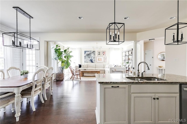 kitchen featuring a chandelier, dark wood-style flooring, stone counters, and a sink