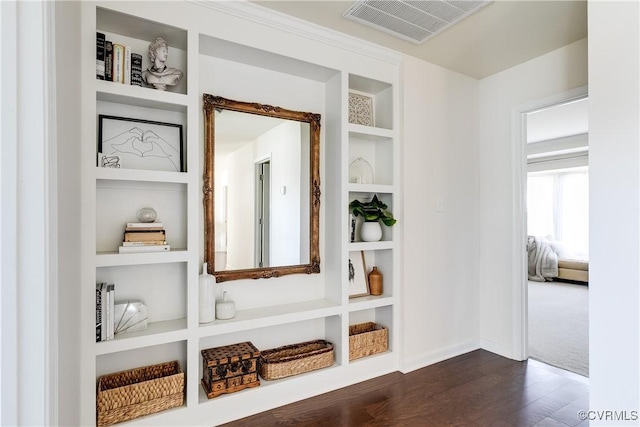 interior space with baseboards, built in shelves, visible vents, and dark wood-type flooring