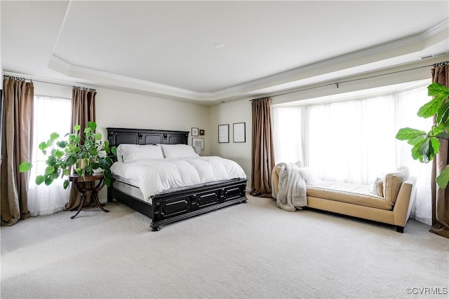 bedroom with light carpet, a tray ceiling, and ornamental molding