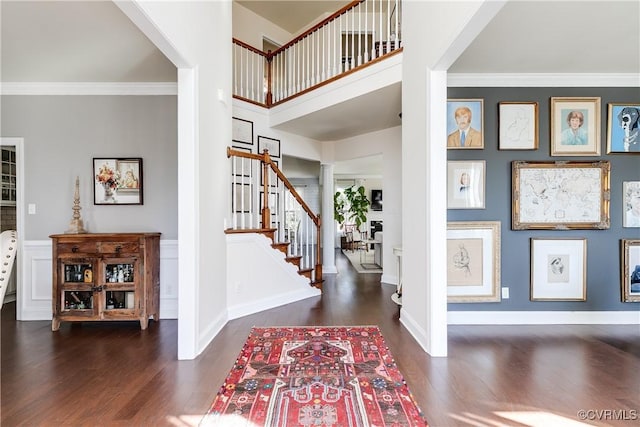 entryway featuring ornamental molding, stairway, wood finished floors, and ornate columns