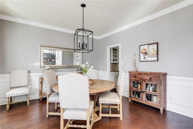 dining area with ornamental molding, dark wood-style flooring, wainscoting, and an inviting chandelier