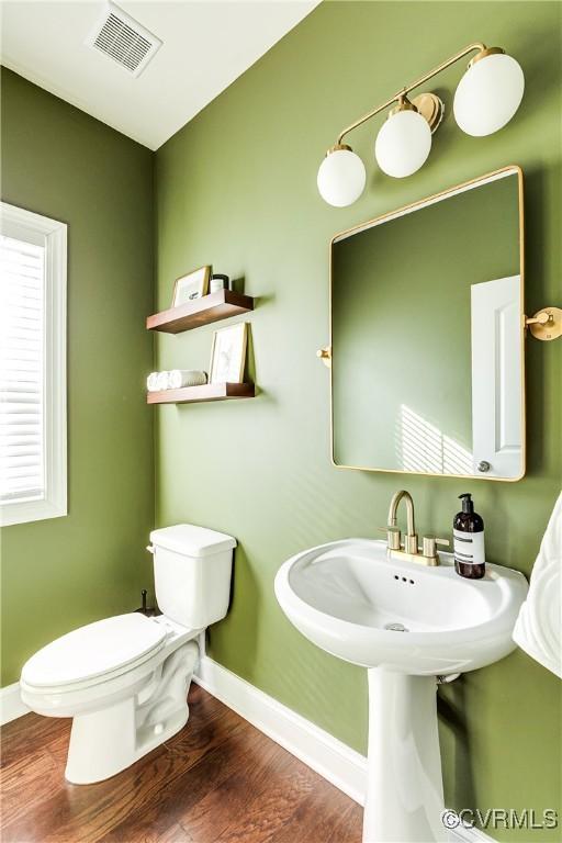 bathroom with toilet, wood finished floors, visible vents, and baseboards