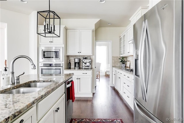 kitchen with stainless steel appliances, dark wood-type flooring, a sink, white cabinetry, and backsplash