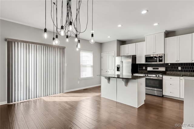 kitchen with appliances with stainless steel finishes, a center island, dark wood-style flooring, and backsplash