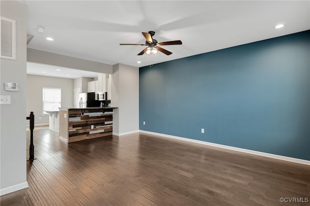 living area with dark wood-style floors, ceiling fan, and baseboards