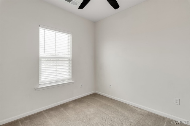 empty room with baseboards, visible vents, a ceiling fan, and light colored carpet