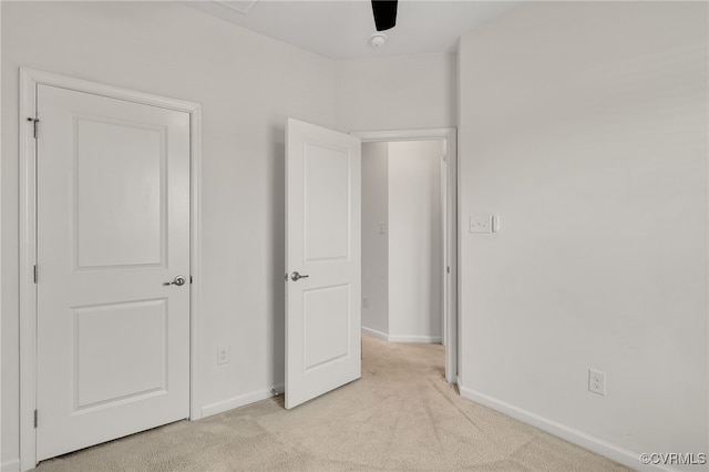 unfurnished bedroom featuring light carpet and baseboards