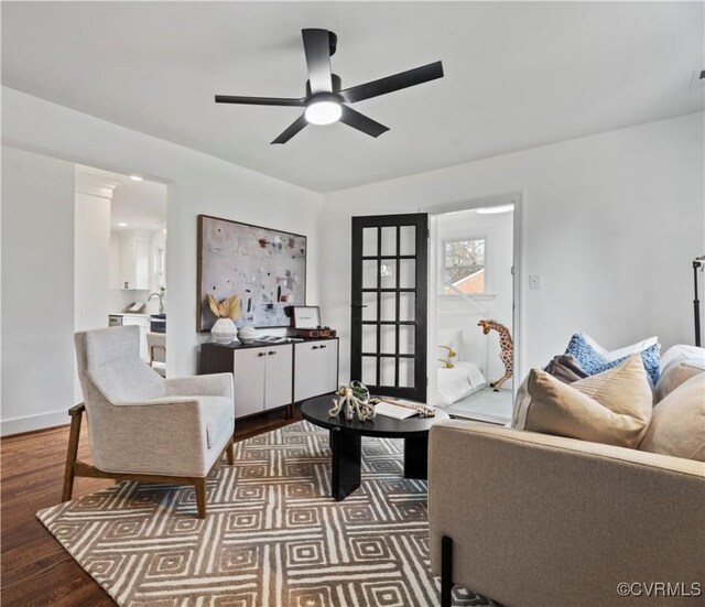 living room featuring baseboards, a ceiling fan, and wood finished floors