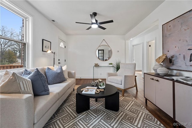 living area featuring dark wood-type flooring, visible vents, and a ceiling fan