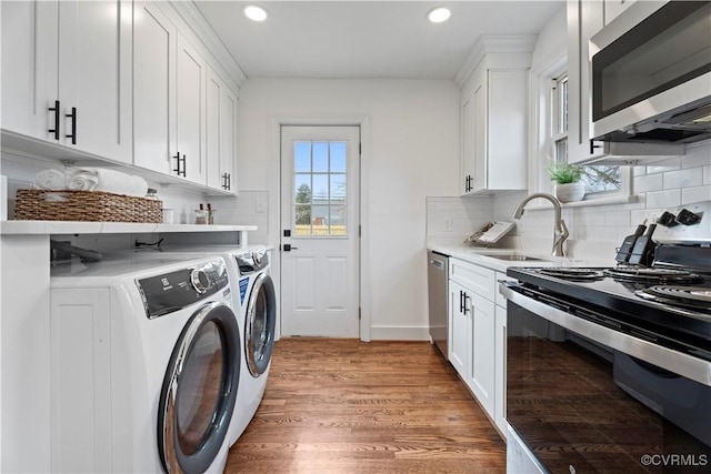 clothes washing area featuring recessed lighting, a sink, separate washer and dryer, light wood-type flooring, and laundry area