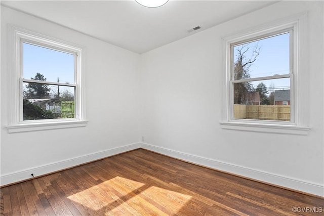 spare room with visible vents, baseboards, and dark wood finished floors