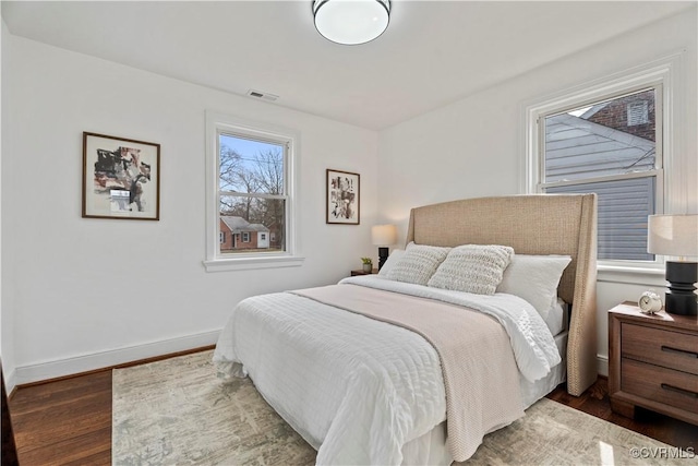 bedroom with baseboards, visible vents, and wood finished floors