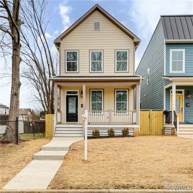 view of front of property featuring a standing seam roof, metal roof, fence, and covered porch