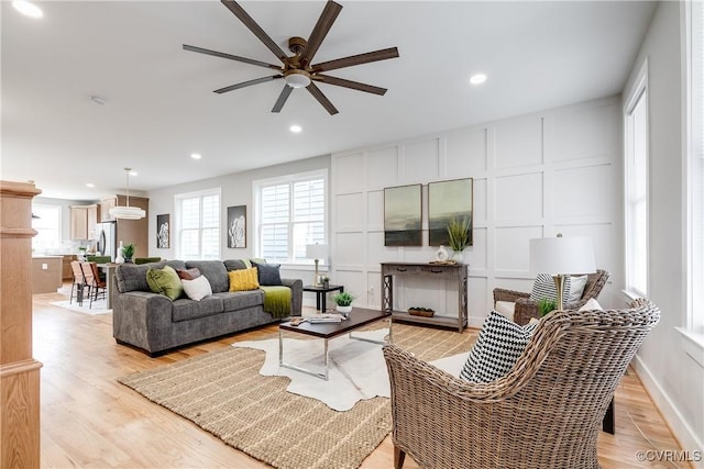 living room featuring light wood finished floors, a decorative wall, and recessed lighting