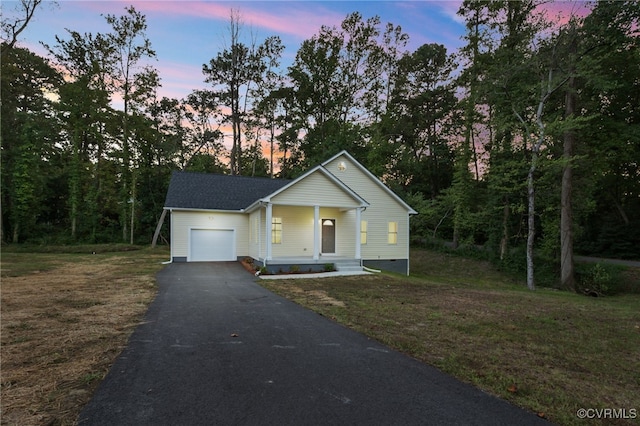 view of front of home featuring a garage, a porch, a front lawn, and aphalt driveway