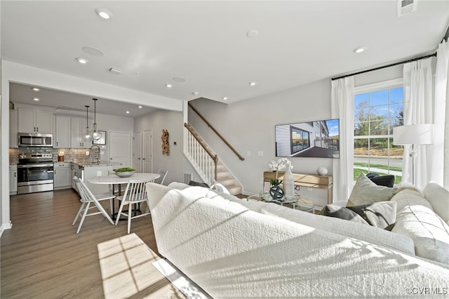 living room with stairs, visible vents, dark wood-style flooring, and recessed lighting