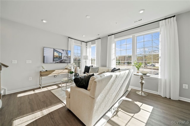 living area with recessed lighting, visible vents, baseboards, and wood finished floors