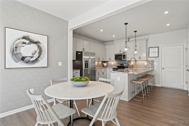 dining space with wallpapered walls, baseboards, wood finished floors, and recessed lighting