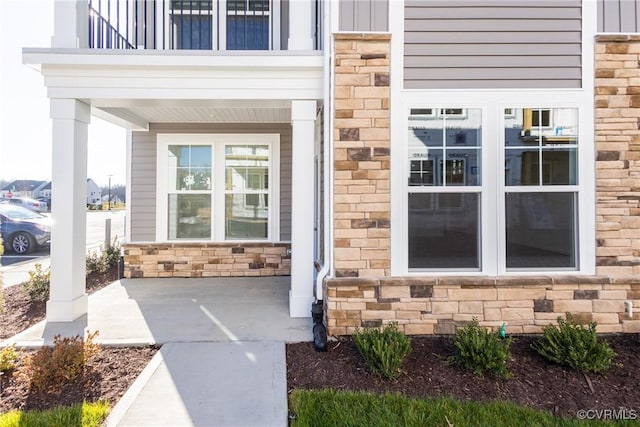 entrance to property featuring stone siding, board and batten siding, and a balcony