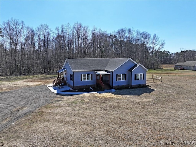 view of front of home featuring a forest view and a shingled roof