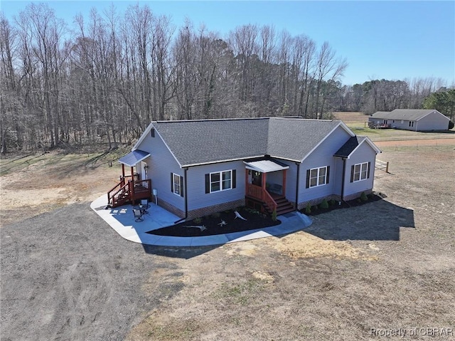 single story home with a forest view and roof with shingles