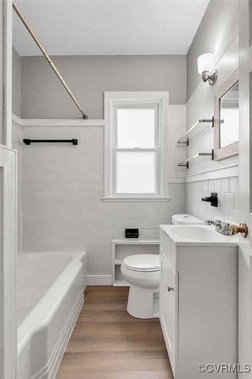 full bathroom with toilet, plenty of natural light, wood finished floors, and vanity