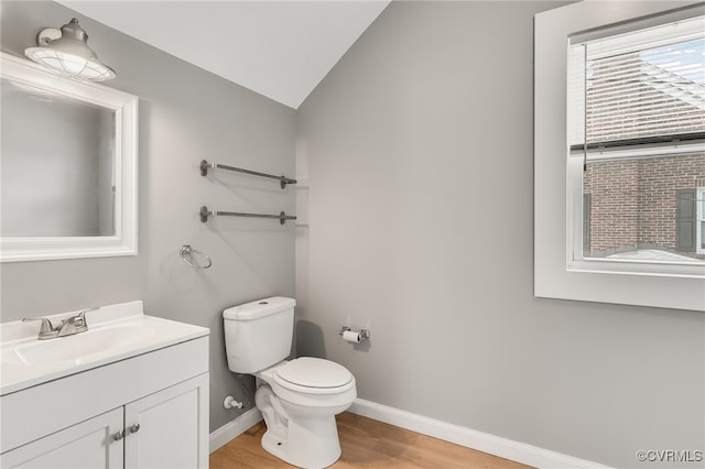 half bath featuring baseboards, lofted ceiling, toilet, wood finished floors, and vanity