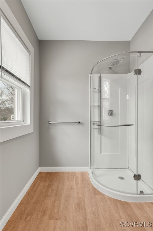 full bath with a stall shower, baseboards, and wood finished floors