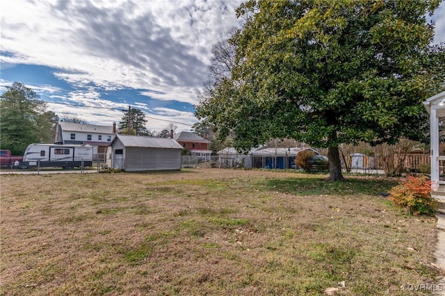 view of yard featuring a shed, fence, and an outdoor structure