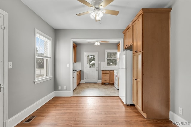 kitchen featuring freestanding refrigerator, baseboards, visible vents, and light wood finished floors