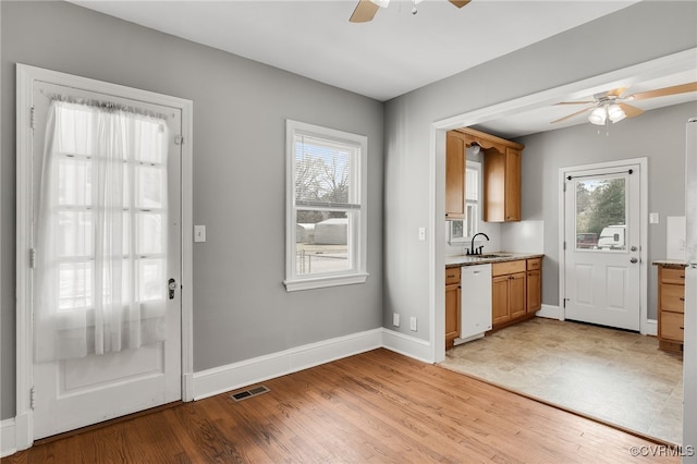 doorway featuring visible vents, a sink, light wood finished floors, and ceiling fan