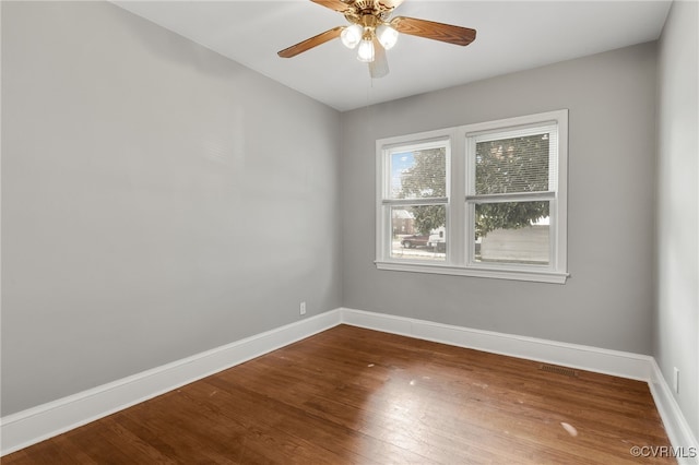 unfurnished room with a ceiling fan, visible vents, baseboards, and wood finished floors