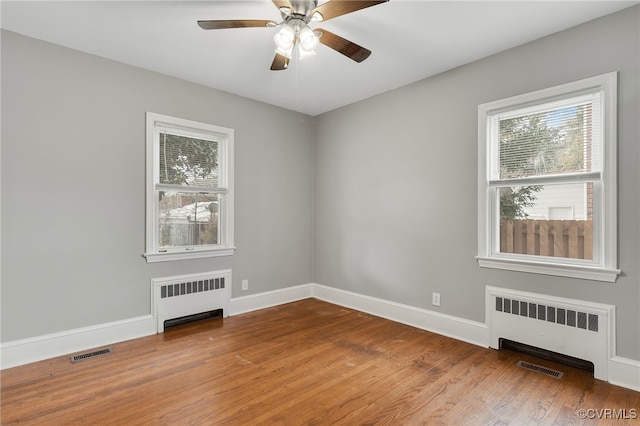 empty room featuring radiator heating unit, visible vents, and a healthy amount of sunlight